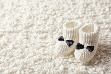 Photo of Handmade baby booties on soft plaid. Space for text