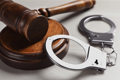 Judge's gavel and handcuffs on white wooden background, closeup. Criminal law concept