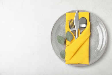 Photo of Plate with cutlery and napkin on light background, top view. Space for text