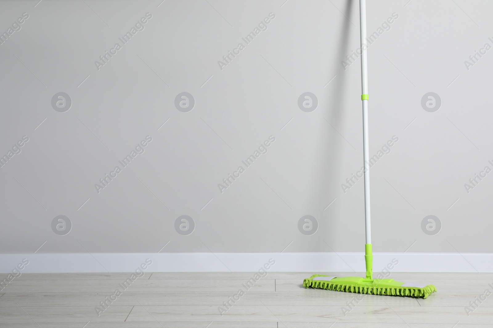 Photo of Mop with plastic handle near wall indoors. Space for text