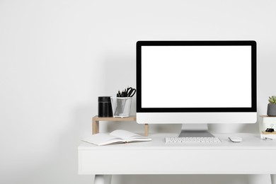 Cozy workspace with computer, houseplant and stationery on wooden desk at home