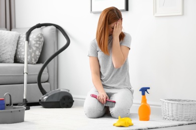 Photo of Tired housewife cleaning carpet at home