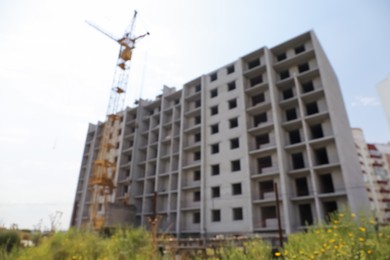 Blurred view of unfinished building and construction crane outdoors