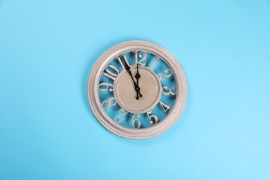 Photo of Stylish wall clock showing five minutes until midnight on turquoise background, top view. New Year countdown
