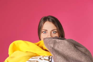 Photo of Young woman holding pile of dirty laundry on color background