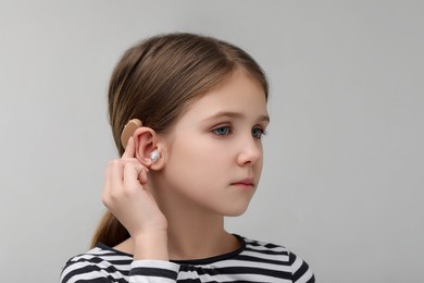 Photo of Little girl with hearing aid on grey background