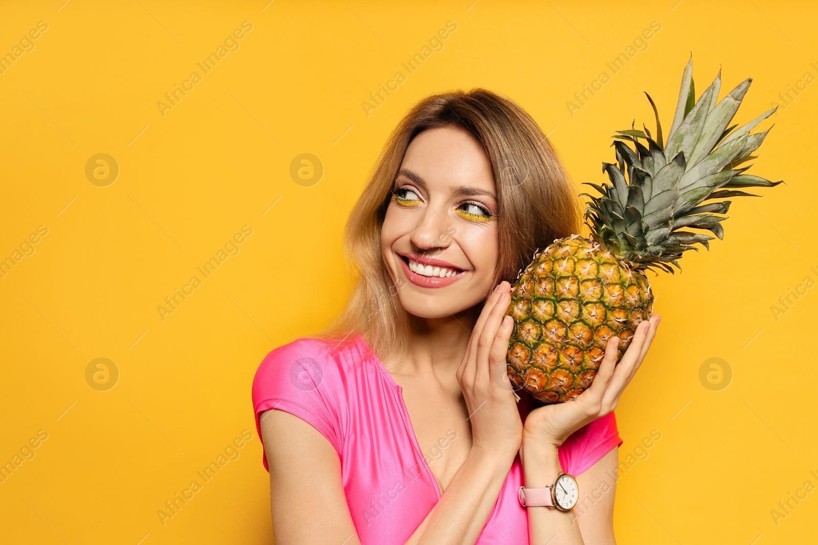 Photo of Young woman with fresh pineapple on yellow background, space for text. Exotic fruit