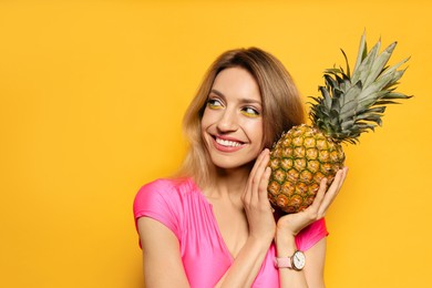 Photo of Young woman with fresh pineapple on yellow background, space for text. Exotic fruit