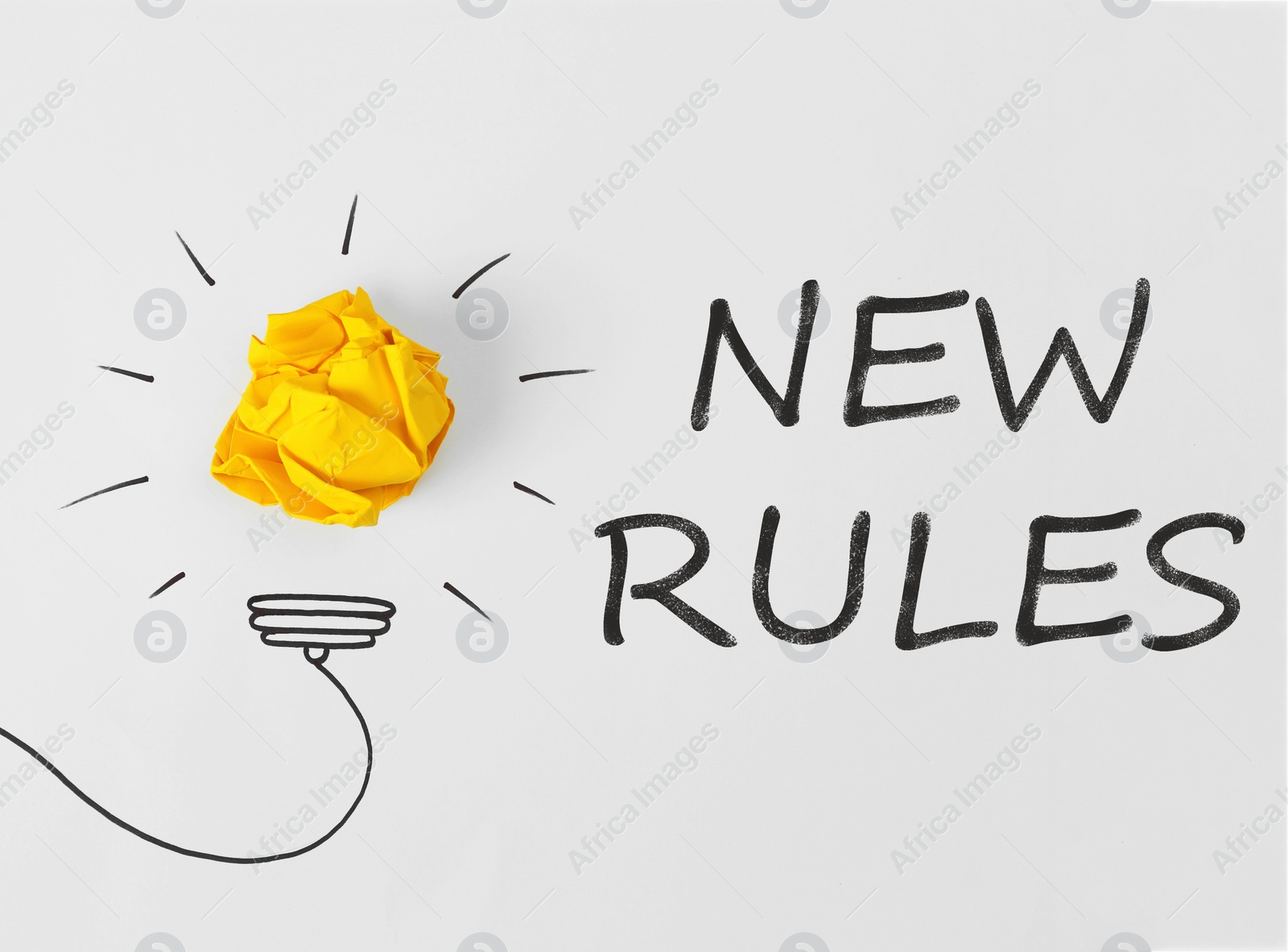 Image of Composition with crumpled paper ball, drawing of lamp bulb and text NEW RULES on white background, top view