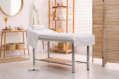 Photo of Comfortable massage table with clean towels in spa center