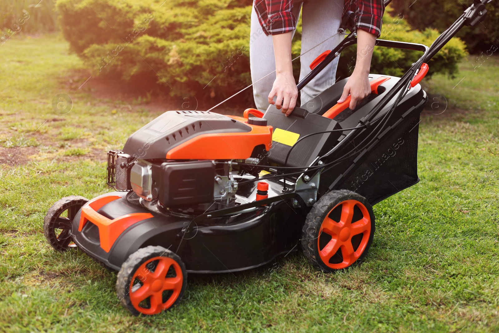 Photo of Woman with modern lawn mower in garden, closeup