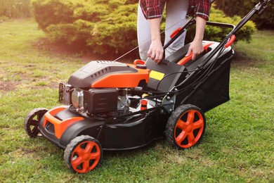 Photo of Woman with modern lawn mower in garden, closeup