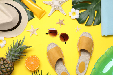 Beach accessories on yellow background, flat lay