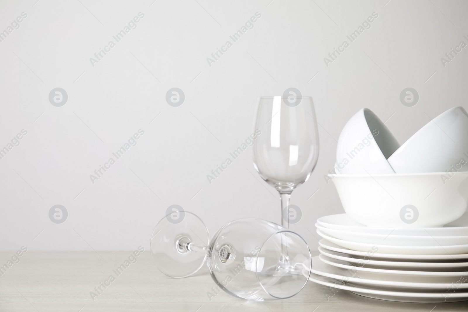 Photo of Clean plates, bowls and glasses on table against white background. Space for text