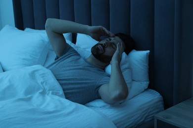 Photo of Man suffering from headache in bed at night