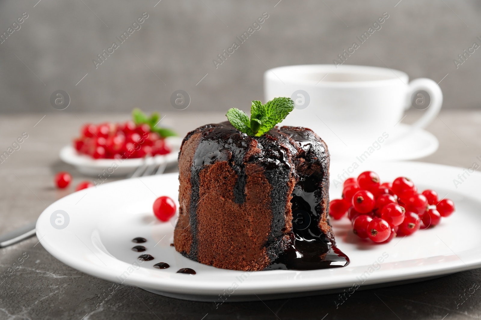 Photo of Delicious warm chocolate lava cake with mint and berries on marble table, closeup