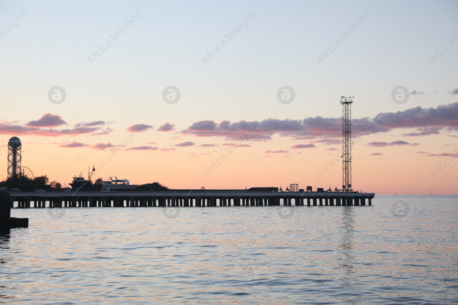 Photo of Picturesque view of pier in sea under beautiful sky at sunset