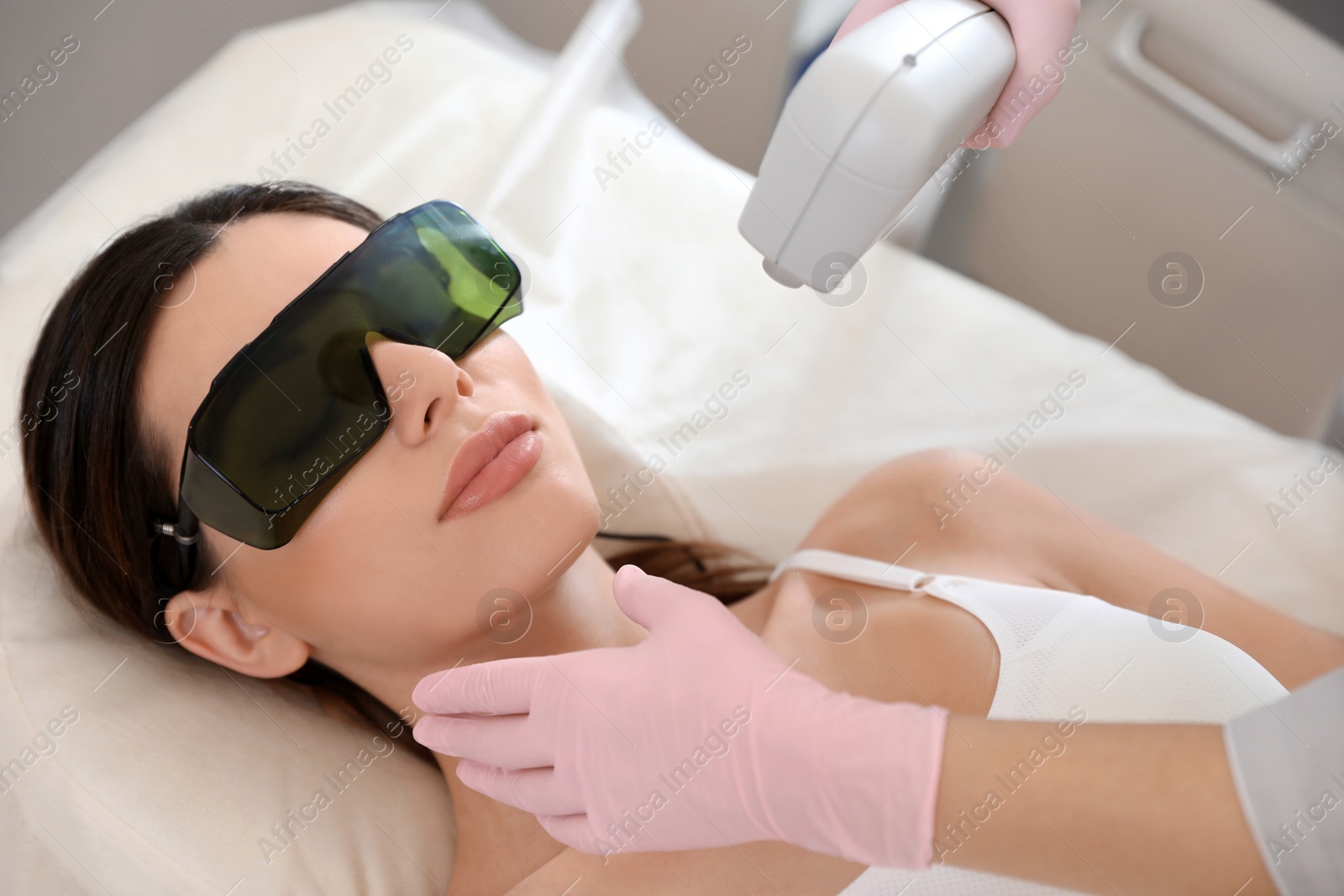 Photo of Young woman undergoing laser epilation procedure in beauty salon