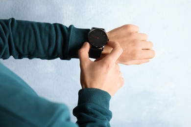 Man with stylish wrist watch on color background, closeup. Time management