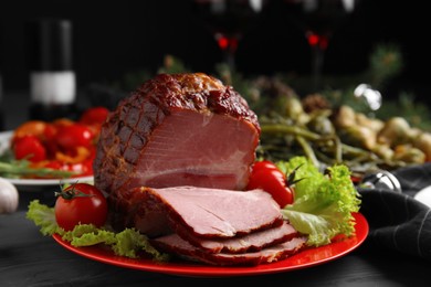 Photo of Plate with delicious ham, lettuce and tomatoes on black wooden table