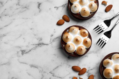 Photo of Delicious salted caramel chocolate tarts with meringue and almonds on white marble table, flat lay. Space for text