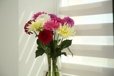 Bouquet of beautiful Dahlia flowers in vase near window indoors