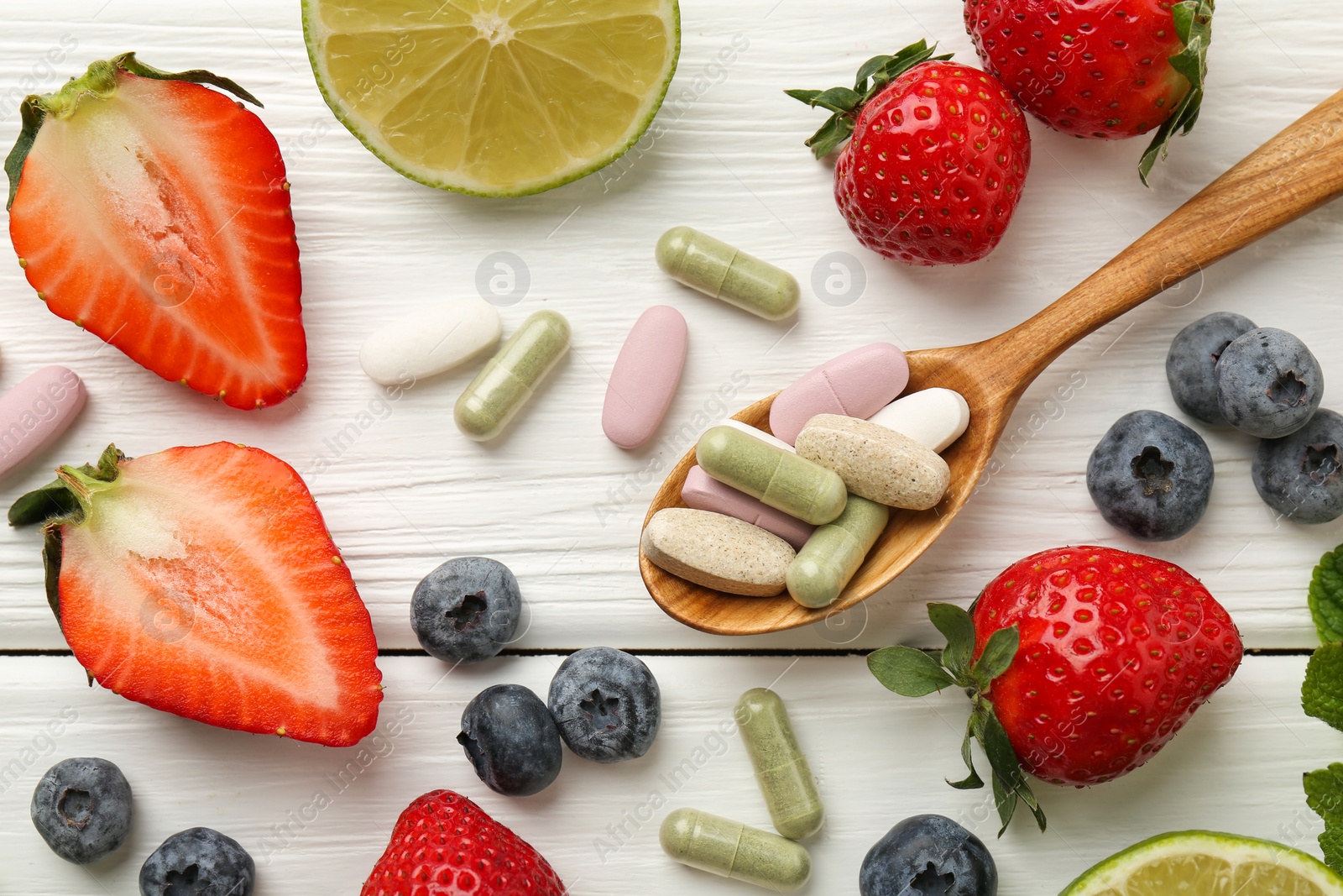 Photo of Different vitamin pills and fresh fruits on white wooden table, flat lay