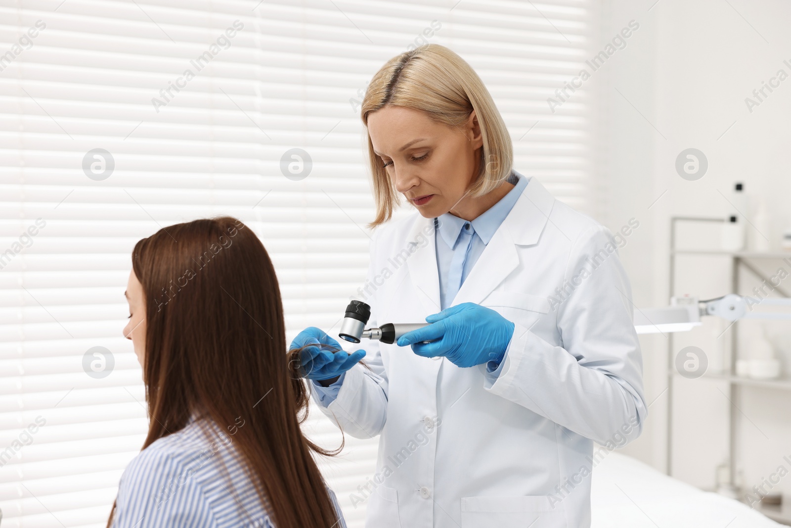 Photo of Trichologist with dermatoscope examining patient`s hair in clinic