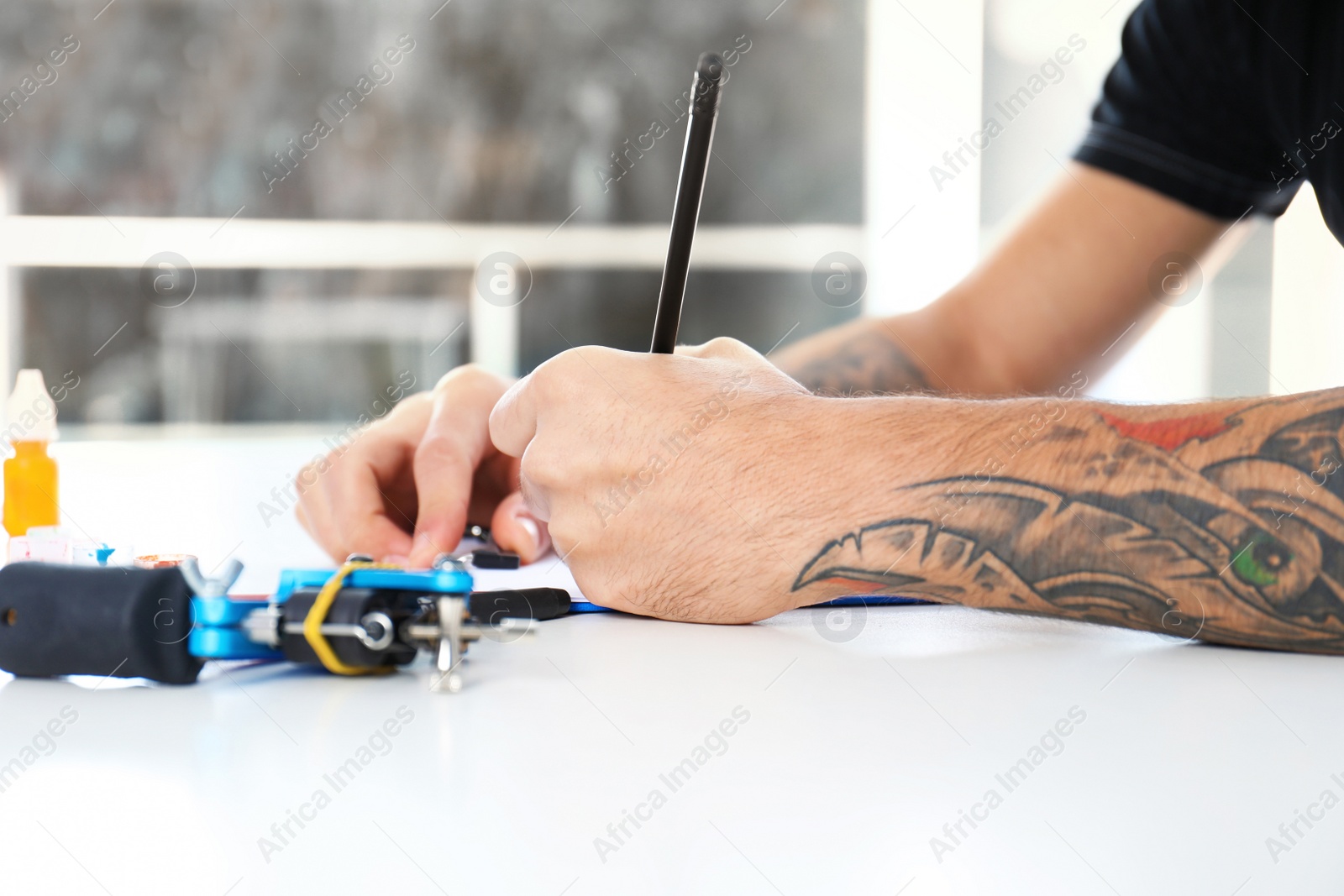 Photo of Professional tattoo artist drawing sketch at table indoors, closeup