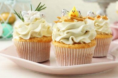 Photo of Tasty Easter cupcakes with vanilla cream on light wooden table