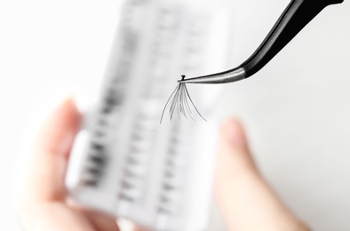 Photo of Woman holding tweezers with false eyelash, closeup