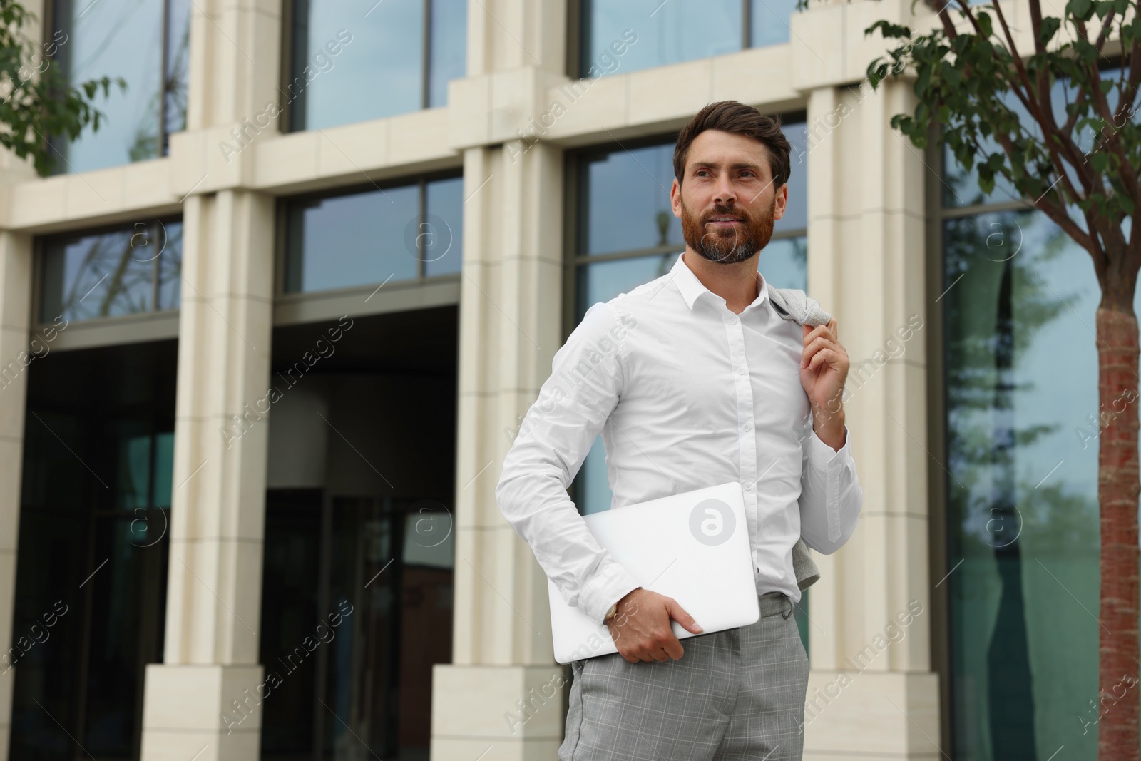 Photo of Handsome businessman with laptop on city street