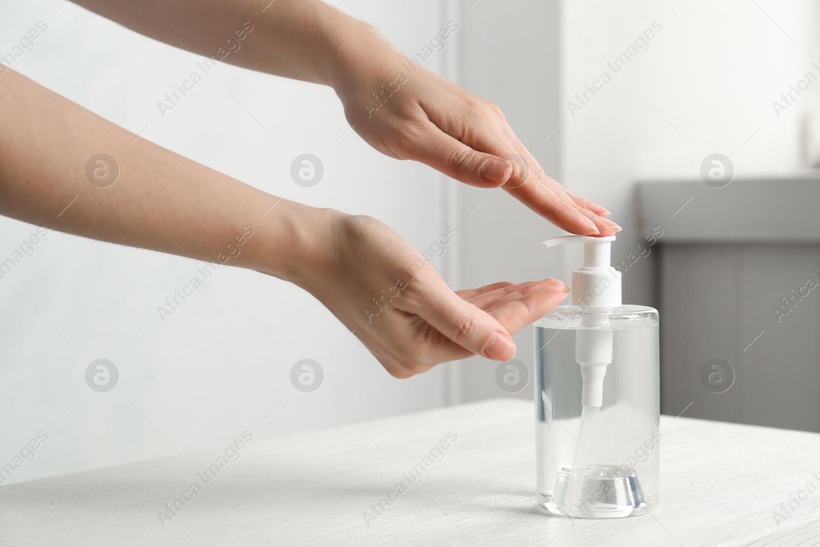 Photo of Woman applying antiseptic gel on hand indoors, closeup