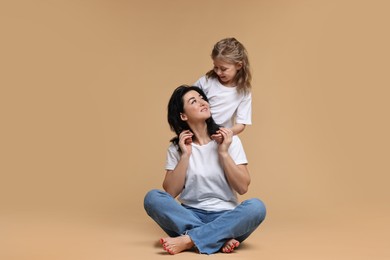 Beautiful mother with little daughter on beige background