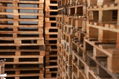 Image of Many empty wooden pallets stacked in warehouse, closeup. Space for text