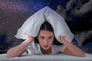 Image of Annoyed young woman covering ears with pillow and beautiful starry sky at night on background