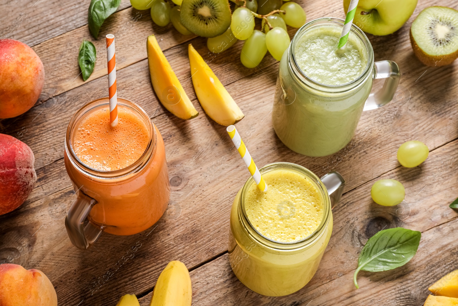 Photo of Mason jars of different tasty smoothies and fresh ingredients on wooden table, above view