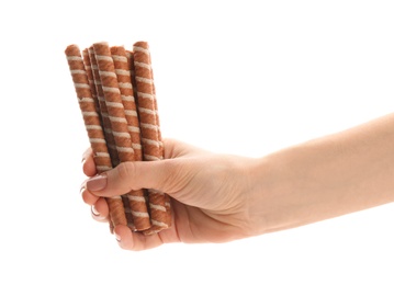 Photo of Woman holding tasty wafer roll sticks on white background, closeup. Crispy food