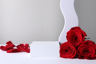 Stylish presentation for product. Beautiful red roses, petals and geometric figures on light background, space for text