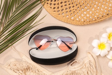 Photo of Flat lay composition with stylish sunglasses in black leather case on sand