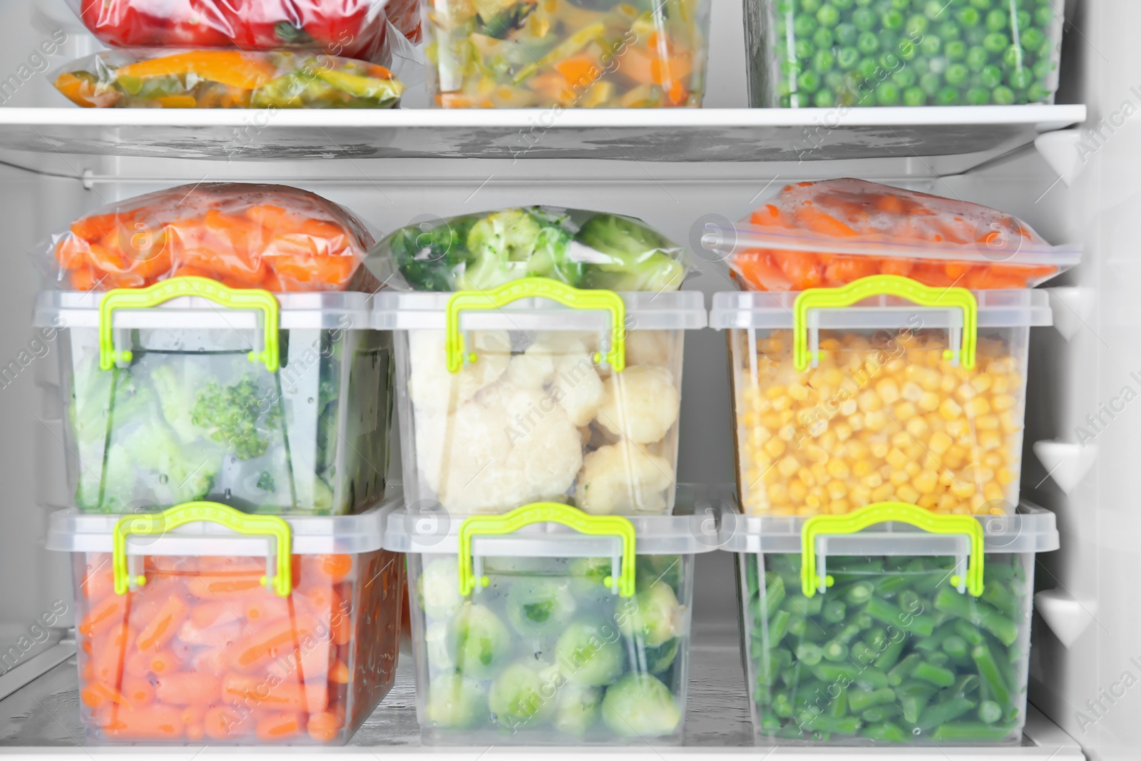 Photo of Containers with deep frozen vegetables in refrigerator