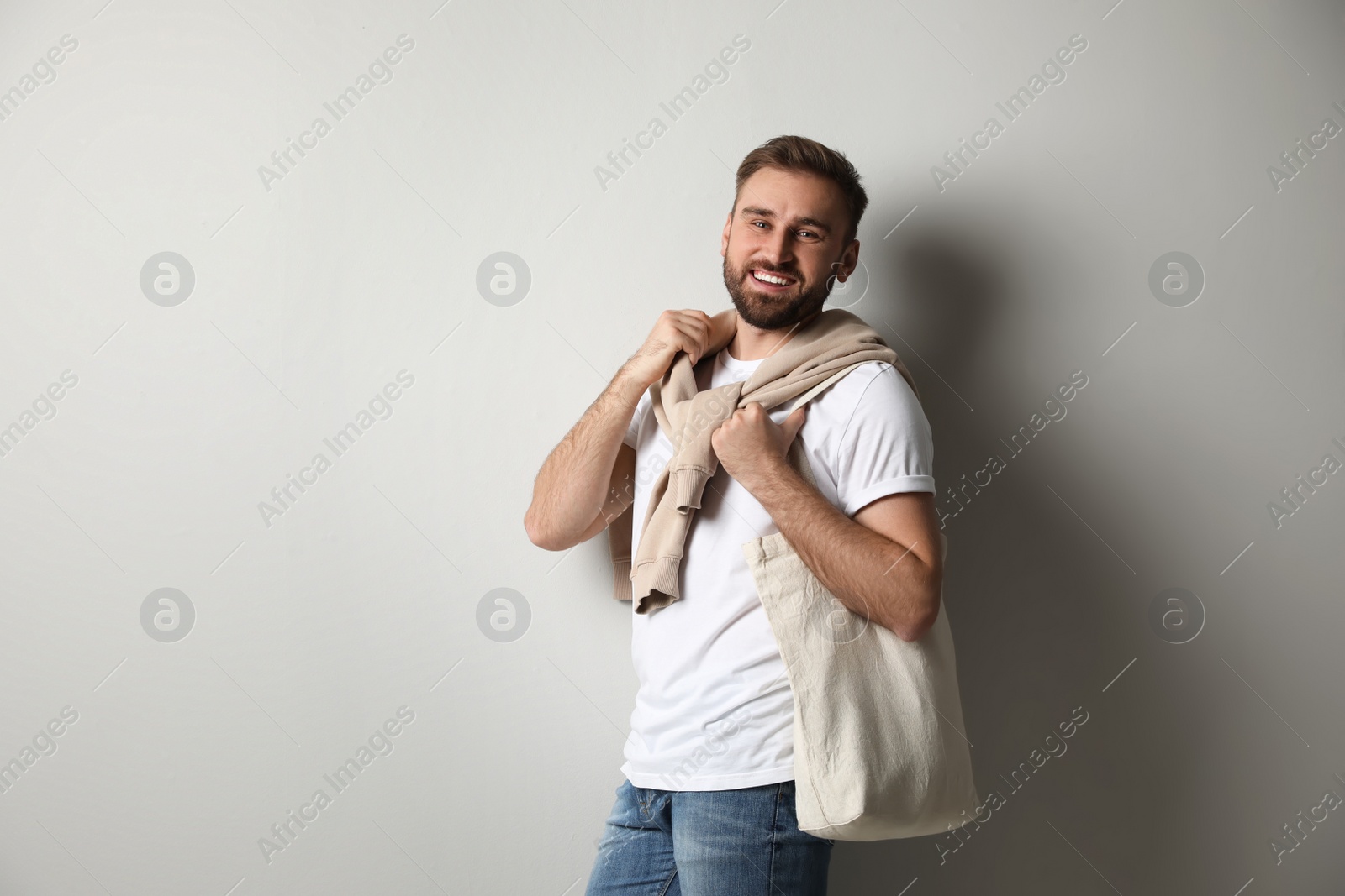 Photo of Happy man with eco bag on light background. Space for text