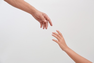 Photo of Man and woman giving each other hands on light background. Concept of support and help