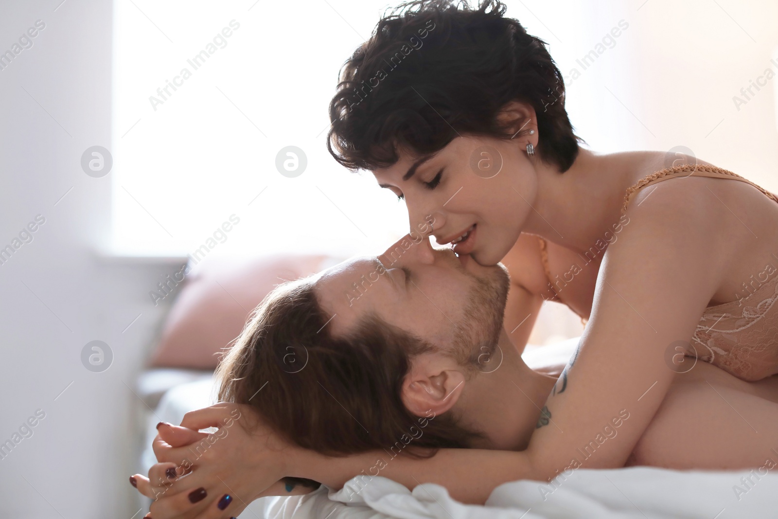 Photo of Lovely young couple being intimate on bed at home