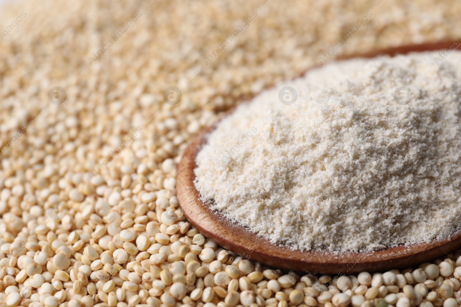 Photo of Wooden spoon with quinoa flour on seeds, closeup