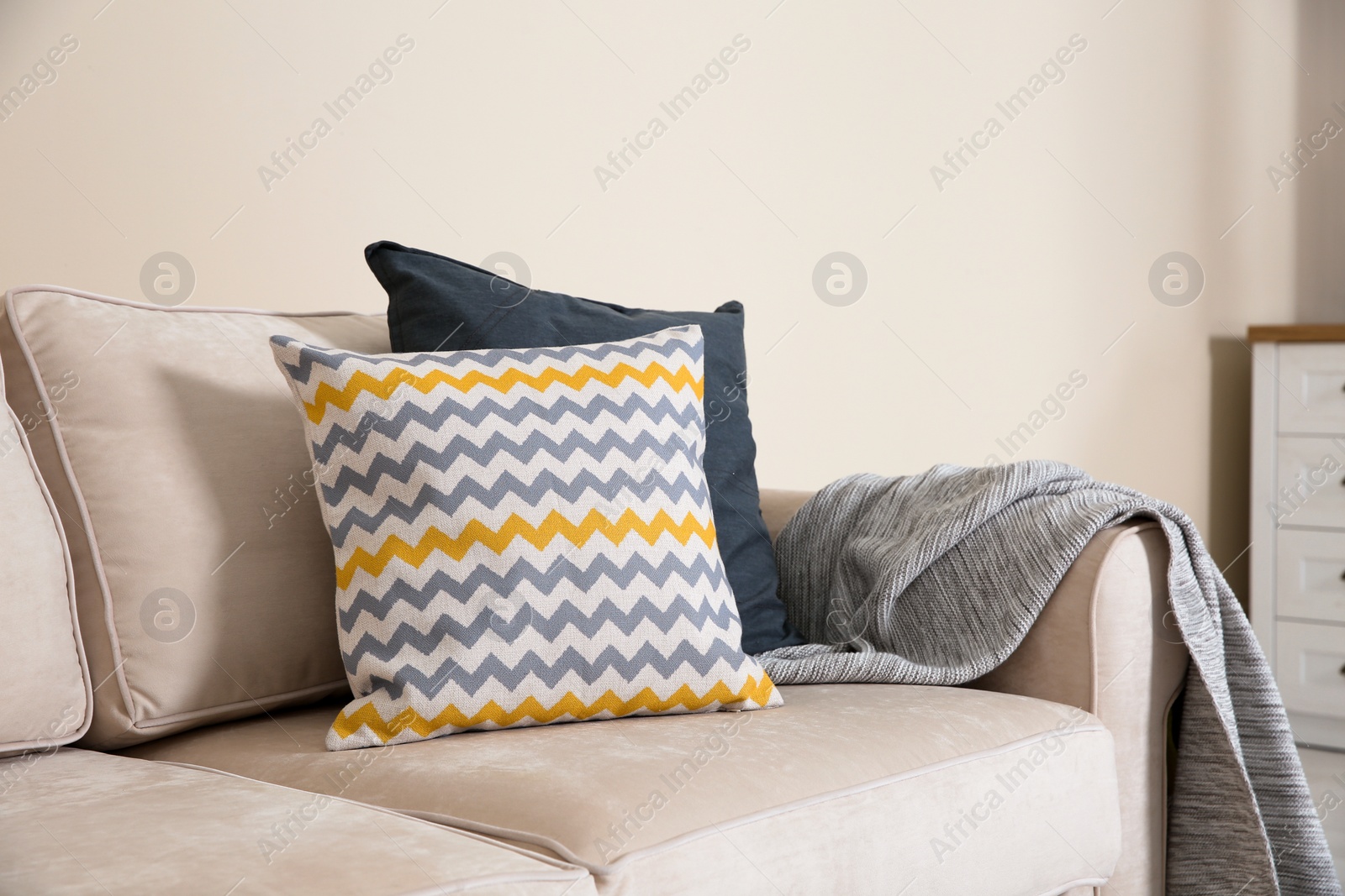 Photo of Cozy sofa with pillows and plaid near light wall. Idea for living room interior design