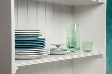 White shelving unit with set of dishware near wall