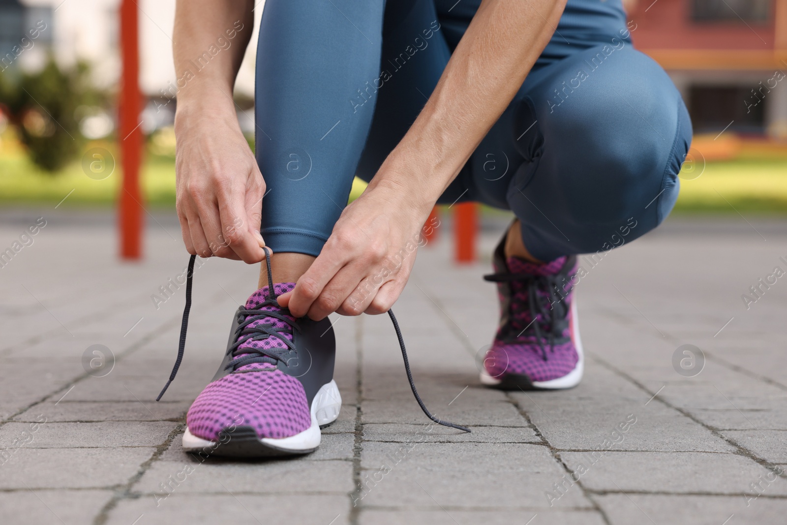 Photo of Woman tying shoelaces before training outdoors, closeup