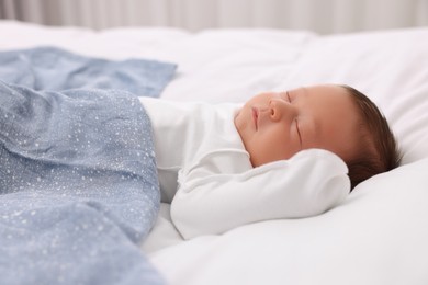 Cute newborn baby sleeping under blue blanket on bed