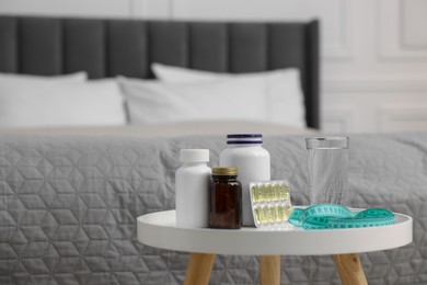 Photo of Pills, measuring tape and glass of water on white table in room, space for text. Weight loss